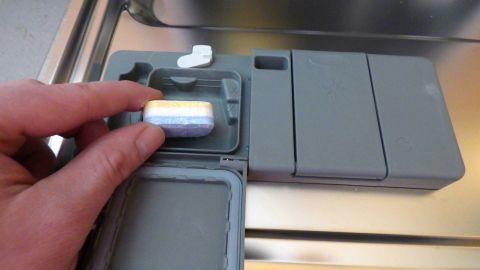 Ein Nutzer legt eine 3in1-Geschirrspüler-Tab in das Fach eines Geschirrspülers, um Geschirr effizient zu reinigen.