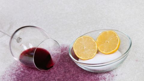 Ein umgekipptes Glas mit Rotwein verschüttet Flüssigkeit auf einem Untergrund, während zwei Zitronenscheiben und Salz daneben liegen.