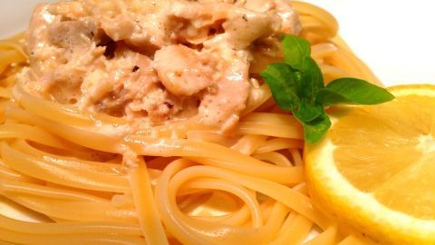 Eine köstliche Portion Spaghetti liegt auf einem Teller, bedeckt mit einer cremigen Lachs-Sahnesoße und frischen Kräutern.
