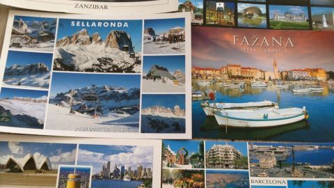 Postkarten aus verschiedenen Orten liegen verteilt auf einem Tisch, jeder zeigt einzigartige Landschaften und Stadtansichten, ideal für Postcrossing.