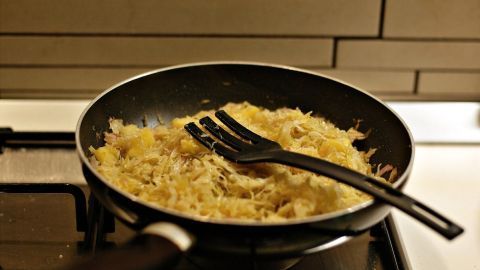 In einer Pfanne wird köstliches Sauerkraut mit einem schwarzen Pfannenwender zubereitet, umgeben von einer modernen Küchenumgebung.