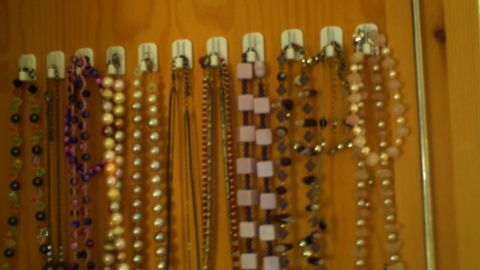 Modeschmuck Ketten hängen ordentlich an einer Wand, gut sichtbar sortiert, um einen übersichtlichen Blick zu bieten.