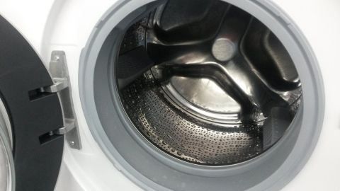 Eine geöffnete Waschmaschine zeigt die saubere Trommel, bereit zur Reinigung, in einem hellen Raum.