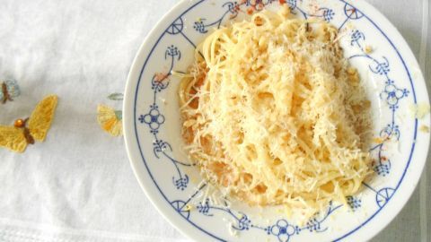 Spaghetti liegt in einer weißen Schüssel, umgeben von einem Tablett mit einer Zitronenscheibe, bereit zum Servieren.