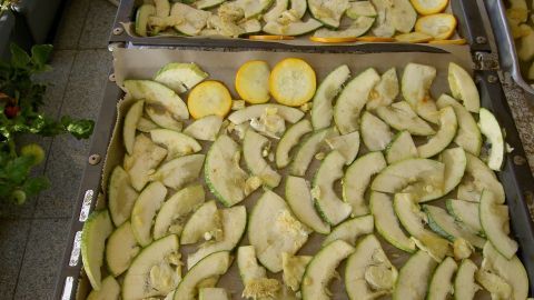 Zucchini-Chips liegen gleichmäßig auf zwei Backblechen und werden im Backofen knusprig gebacken.