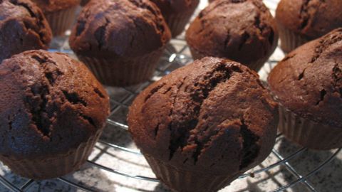 Schoko-Muffins kühlen auf einem Metallgitter ab, frisch gebacken in einer Küche auf einer Arbeitsplatte.