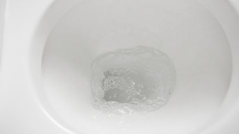 Eine Tiefspültoilette zeigt einen kreisenden Wasserstrahl im Wasser, der Spritzer im Badezimmer verhindert.