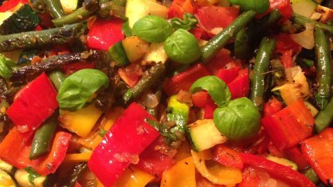 Bunte Gemüsestücke aus Zucchini, Tomaten und Paprika werden in einer Pfanne sautiert, um ein mediterranes Gericht zu kreieren.