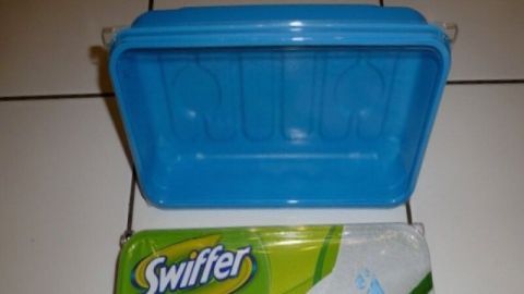 Eine leere Swiffer-Box steht offen auf einem Fliesenboden, neben einer Packung Reinigungstücher.