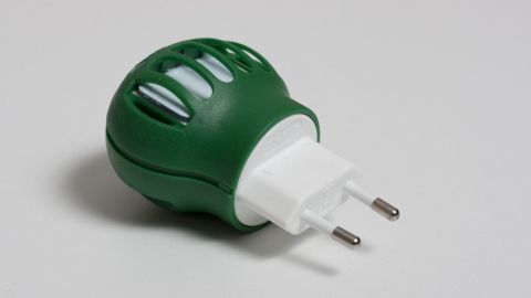 Ein Mückenstecker in Grün mit weißen Einsätzen steht bereit, um Stechmücken in einem Innenraum abzuwehren.