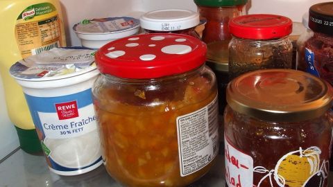 Ein Kühlschrank voller unterschiedlicher Gläser und Behälter, während man ihn ausmistet und reinigt, um Platz zu schaffen.