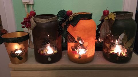 Kreative Windlichter aus Gläsern leuchten sanft auf einem Tisch und schaffen eine herbstliche Atmosphäre.