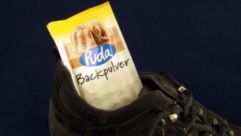 Ein schwarzer Turnschuh mit einem Päckchen Backpulver steckt im Innenteil. Dies zeigt eine Methode gegen Müffel-Turnschuhe.