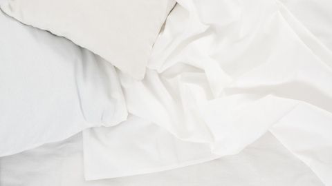 Weiße Bettwäsche und ein Kissen liegen auf dem Bett, bereit zur Reinigung von Blutflecken.