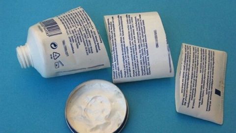 Plastiktuben liegen verstreut auf einer blauen Unterlage, einige sind geöffnet und zeigen den Inhalt, bereit zur Wiederverwertung.