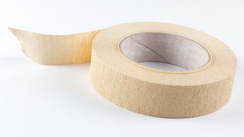 Eine Rolle Kreppband liegt bereit, während ein Stück abgerollt wird, um Etiketten zum Einfrieren anzubringen.