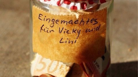 Ein Einmachglas mit rotem Deckel enthält Geldgeschenke und trägt ein Etikett mit "Eingemachtes für Vicky, wild Lini!"
