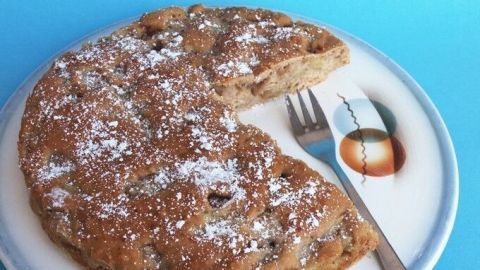 Auf einem Teller liegt ein Apfelkuchen mit Stevia, der leicht angeschnitten ist, um die saftige Füllung zu zeigen.