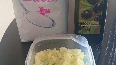 Ein Behälter mit Peeling-Mischung aus Zucker und Olivenöl steht auf einem Tisch, um eingewachsene Haare zu behandeln.