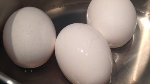 Drei weiße Eier liegen in einem Topf mit Wasser, während sie energiesparend gekocht werden.