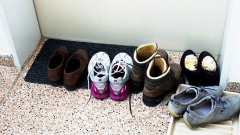 Im Treppenhaus stehen verschiedene Schuhe auf einem Fußabstreifer, was die Gefahren durch Brandlast deutlich macht.