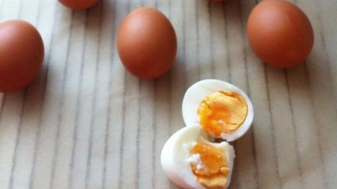 Eier liegen auf einer Oberfläche, während eines aufgeschnitten und gekocht ist, mit weichem Eigelb sichtbar.