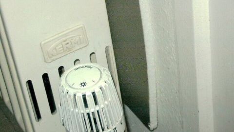 Ein Heizkörper mit Thermostat steht nah an einer Wand, die mit Dämmmaterial versehen ist, um Heizkosten zu sparen.