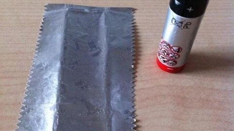 Ein Kaugummipapier liegt neben einer Batterie, bereit zum Feuer machen, um eine improvisierte Zündquelle zu schaffen.
