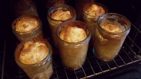 Sechs Apfelkuchen im Glas stehen in einem Ofen und backen goldbraun in einem warmen, gemütlichen Umfeld.