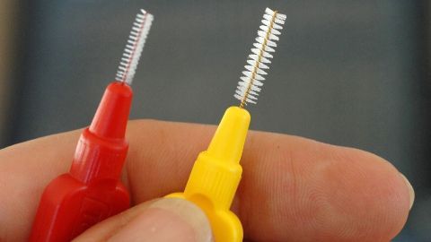 Zwei Reinigungshilfen für Ohrstecker-Verschlüsse werden in der Hand gehalten, bereit für die Pflege von Schmuckstücken.