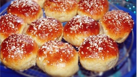 Süße Brötchen liegen auf einem blauen Teller, frisch gebacken mit goldbrauner Kruste und Puderzucker bestreut.