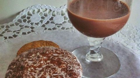 Ein Glas Nutella Likör steht auf einem Tisch, begleitet von einem Keks, auf einer weißen, dekorativen Serviette.
