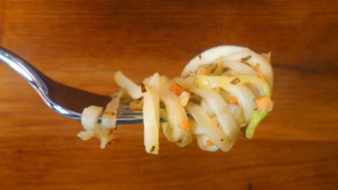 Zucchinispaghetti liegen auf einer Gabel, umgeben von einer Holzoberfläche, bereit zum Genießen mit Rosmarin-Mandel-Butter.