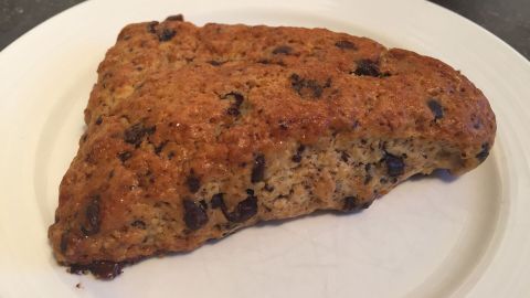 Ein frisch gebackener Schokoladen Scone liegt auf einem weißen Teller und wartet darauf, genossen zu werden.
