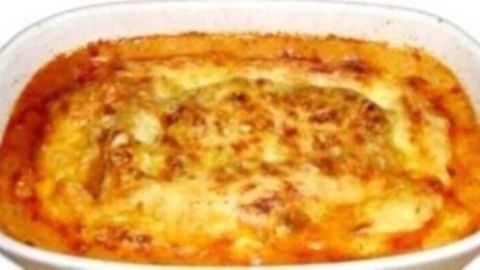 Eine goldbraun gebackene Lasagne Bolognese liegt in einer weißen Auflaufform, umgeben von einer warmen Küche.