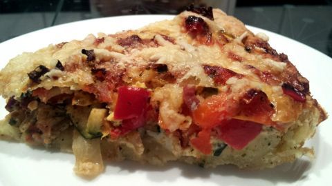 Die glutenfreie Gemüse-Quiche liegt auf einem weißen Teller, goldbraun gebacken mit frischen Gemüse durchzogen.