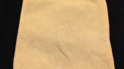 Ein abgerundetes, flauschiges Tuch liegt auf einer dunklen Jeans, um Knitterfalten unterwegs wegzuwischen.