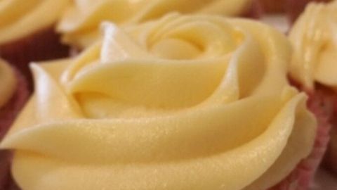 Leckere Cupcakes mit zartem Frischkäse-Frosting in Rosenform stehen auf einem Teller und laden zum Genießen ein.