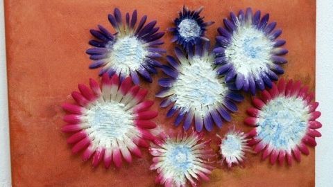 Farbenfrohe Plastikblumen formen ein Acrylbild, das lebendige Blüten auf einem orangefarbenen Hintergrund zeigt.