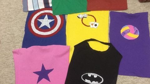 Bunte Superhelden-Capes liegen ordentlich auf dem Boden, bereit für den Kindergeburtstag und das Spielen.