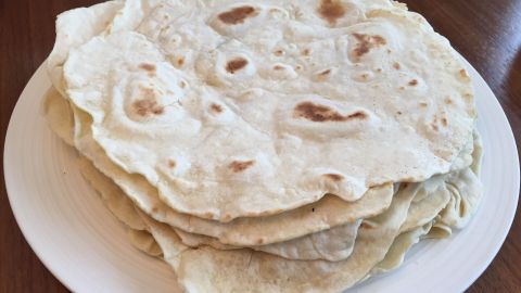 Weizen-Tortillas liegen auf einem Teller, während sie auf einem Tisch in einer gemütlichen Küche serviert werden.