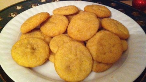 Goldene, runde Kuhbonbon-Karamell Plätzchen liegen auf einem weißen Teller, umgeben von festlichem Weihnachtsschmuck.