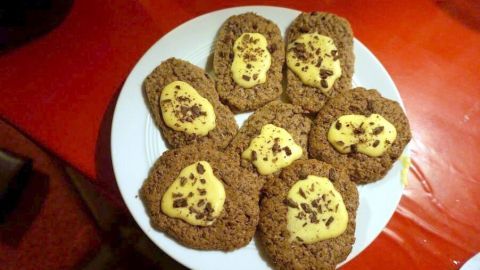 Auf einem weißen Teller liegen mehrere Butterbrote, die mit einer gelben Creme dekoriert sind und Schokoladenstückchen enthalten.