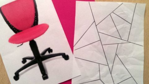 Ein pinkes Papier liegt neben einem Bild eines Bürostuhls und einem Puzzle mit geometrischen Formen.