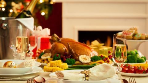 Ein festlich gedeckter Tisch mit abwechslungsreichem Essen, der zu den Feiertagen einlädt, während der Kamin im Hintergrund brennt.