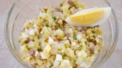 Ein farbenfrohes Herings-Häckerle mit einem Stück Ei und Zitrone in einer Schüssel, umgeben von frischen Zutaten.