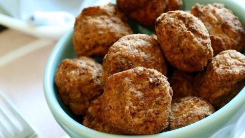 Schmackhafte glutenfreie Fleischbällchen liegen in einer grünen Schüssel, umgeben von Besteck auf einem gedeckten Tisch.