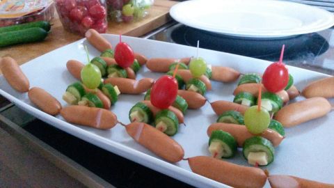 Wurst-Autos auf einer Platte sind kreativ angerichtet, mit Gemüse und Kirschtomaten als Dekoration in einer Küche.