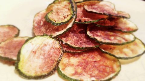 Knusprige Zucchini Chips liegen auf einem Teller, goldbraun und appetitlich angeordnet, ideal für einen Snack.