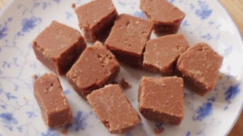 Kleine, quadratische Schokobonbons liegen auf einem dekorativen Teller, bereit zum Genießen in einer gemütlichen Küche.